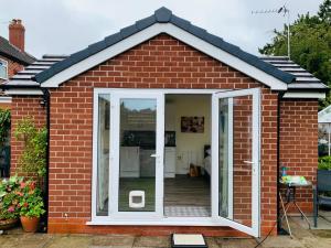 a small red brick house with a sliding glass door at Rose View- a lovely private 1 Bed Bungalow in Sale in Sale