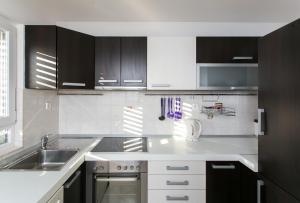 una cocina con armarios en blanco y negro y fregadero en Apartments Marlo, en Dubrovnik