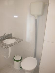 a white bathroom with a toilet and a sink at Hotel Mecejana in Boa Vista