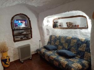 ein Wohnzimmer mit einem Sofa und einem TV in der Unterkunft Cueva Las Rosas-VTAR/GR/02108 in Guadix