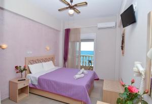 a bedroom with a purple bed and a balcony at Agali Hotel in Limenaria