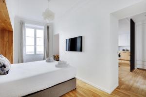 a white bedroom with a large bed and a tv on the wall at Pick A Flat's Apartment in Marais/Oberkampf - bvd du Temple in Paris