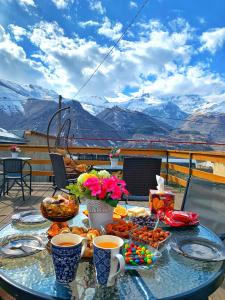 - une table avec de la nourriture et des boissons sur un balcon avec des montagnes dans l'établissement Guesthouse Elia, à Kazbegi