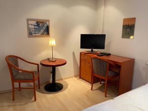 Habitación con escritorio, TV y 2 sillas. en Passage 84 - Hotel & Café, en Heilbad Heiligenstadt
