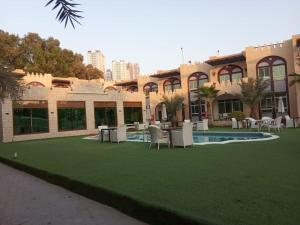 a building with a yard with chairs and a pool at Corniche Palace Hotel in Ajman 
