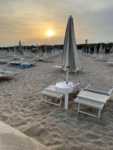 a group of lounge chairs and an umbrella on the beach at Eraclea Palace Hotel 4 stelle S in Eraclea Mare