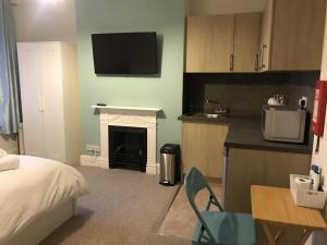 a bedroom with a bed and a kitchen with a fireplace at Poole Stay in Poole