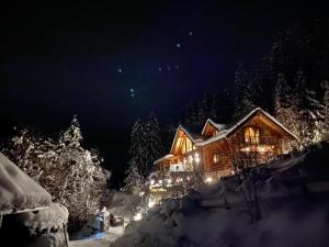 une cabane en rondins avec des lumières dans la neige la nuit dans l'établissement Chalet Caprea, à Bad Kleinkirchheim