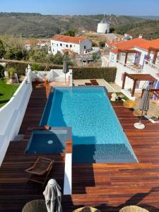 a swimming pool sitting on a wooden deck next to a house at Casas Do Moinho - Turismo De Aldeia in Odeceixe