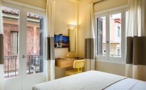 een slaapkamer met een bed, een bureau en ramen bij Athena hotel in Nafplio