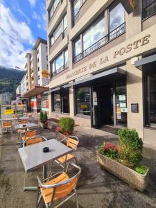 a group of tables and chairs in front of a building at Hôtel de la Poste Martigny - City Center in Martigny-Ville