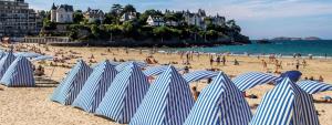 a group of blue and white striped umbrellas on a beach at Studio centre Dinard in Dinard
