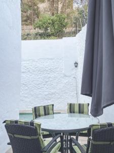 a table with chairs and an umbrella on a patio at Casa El Villa in Zahara de la Sierra