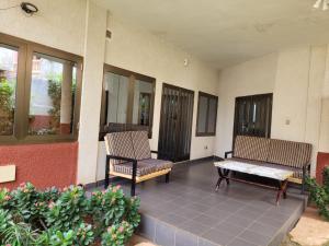 2 Stühle und eine Bank auf einer Terrasse in der Unterkunft Villa Anaël in Porto-Novo