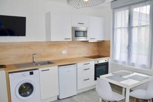 a white kitchen with a sink and a washing machine at Les forges 2 pièces RDC in Avoine