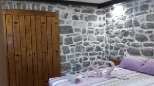a bedroom with stone walls and a bed with swans on it at Apartman Hana in Tivat