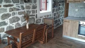 a table and chairs in a kitchen with a stone wall at Apartman Hana in Tivat