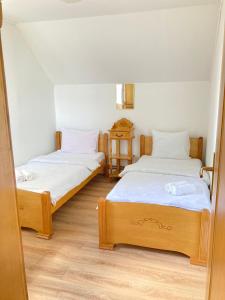 two beds in a room with white walls and wooden floors at Guest House Nena in Žabljak