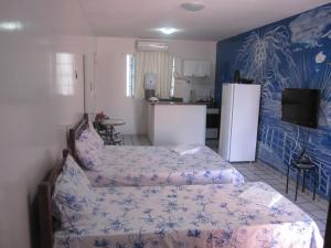 a bedroom with a bed and a kitchen with a refrigerator at Pousada Temporada Maceió in Maceió