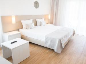 a white bedroom with a white bed and a table at Tavira Monte in Tavira