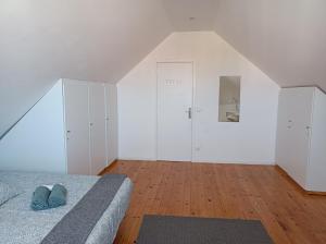 una camera da letto con letto, pareti bianche e pavimenti in legno di Pensão Central ad Aveiro