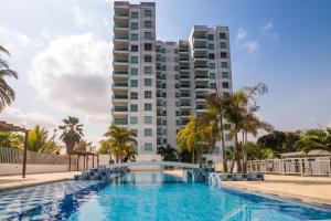 una piscina con un alto edificio sullo sfondo di Magico Apartamento Frente al Mar 3 Habitaciones AR51 a Coveñas