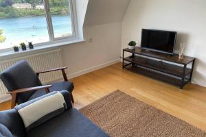 a living room with a couch and a tv at Apartment with stunning views of Menai Strait. in Menai Bridge