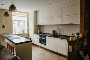 cocina con armarios blancos y encimera en Lovely apartment for families and couples en Liepāja