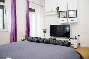 a bedroom with a bed and a tv and purple curtains at White Orchid Pula in Pula