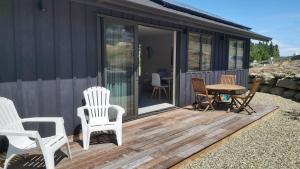 a deck with chairs and a table on a house at Hawea Mountain cottage in Lake Hāwea