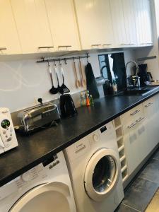 uma cozinha com uma máquina de lavar roupa debaixo de um balcão em Maison de pêcheur de 1820 au cœur du bourg - 3 étoiles em Ouistreham