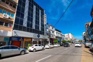 a busy city street with cars parked in front of buildings at Hotel Pouso Alegre in Campo Grande