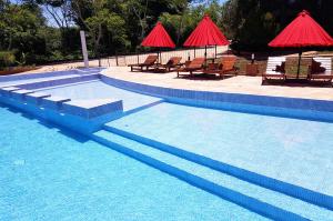 een zwembad met tafels, stoelen en parasols bij Puro Moconá Lodge in El Soberbio