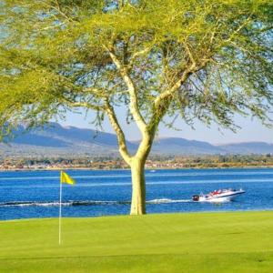 a boat on the water with a tree and a golf course at Pecanwood Golf Estate Home - Hartbeespoort in Hartbeespoort