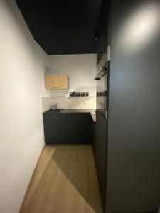 Il comprend une cuisine avec des armoires noires et du parquet. dans l'établissement Apartament 87, à Szczecin