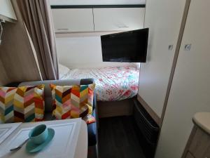 Habitación pequeña con cama y TV. en Caravane tractable en Paliseul