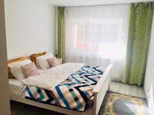 a small bedroom with a bed and a window at Apartament Veverițe in Slănic-Moldova
