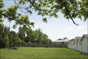 a yard with picnic tables and a fence and trees at Falls Manor Resort in Niagara Falls