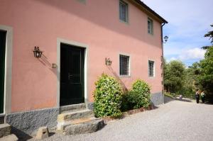 a pink house with a black door on a street at Fattoria di Fubbiano in Collodi