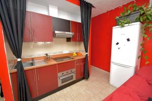 Il comprend une cuisine équipée de placards rouges et d'un réfrigérateur blanc. dans l'établissement Casa Flores, à Arrecife