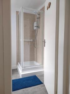 La salle de bains est pourvue d'une douche et d'un tapis bleu. dans l'établissement Shadow's Cottage situated in Fishertown, Nairn., à Nairn