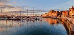 Un grupo de barcos atracados en un puerto con edificios. en Casa Lantoxana Quiet and fully-equipped , ideal for families, en Gijón