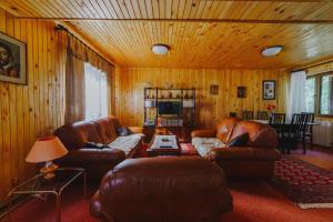 uma sala de estar com sofás de couro e uma televisão em Highlander's House em Žabljak