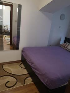 a bedroom with a purple bed and a mirror at Hello Apartment in Skopje