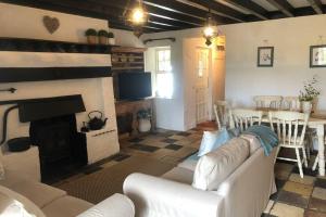 a living room with a white couch and a fireplace at Clannad Cottage in Arboe