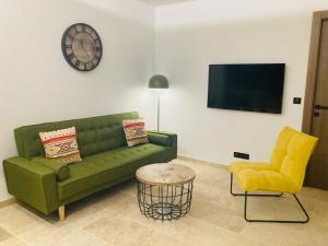 sala de estar con sofá verde y reloj en la pared en La Salamandre, en La Motte