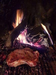 a piece of meat cooking on a grill with fire at Il Fienile Sotto L'Arco in Tavarnelle Val di Pesa