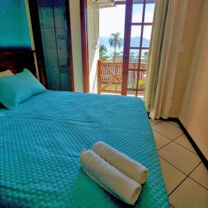 a bed with a green comforter with a pillow on it at Pousada Aquarela do Mar in Abraão