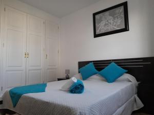 a bedroom with a large bed with blue pillows at Apartamentos Carlota in Puerto del Carmen