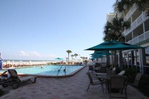 - une piscine avec des tables et des chaises ainsi qu'une plage dans l'établissement Oceanview Studio, à Daytona Beach